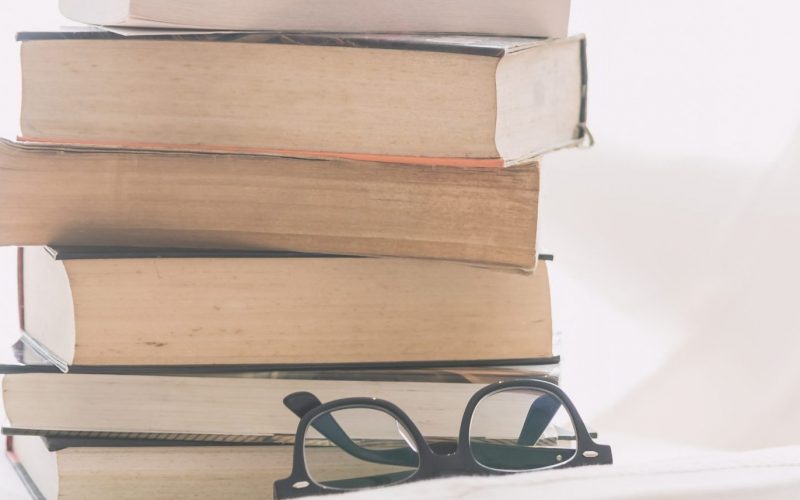 Coffee cup on book and eyeglasses with copy space for text - soft vintage filter